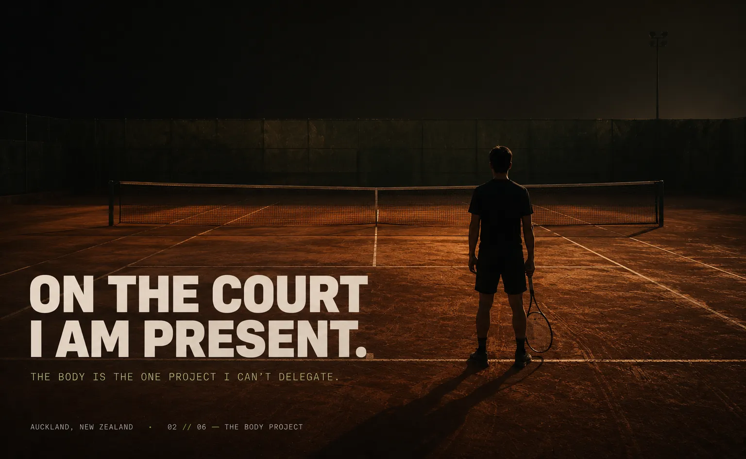 Fitness — back-view silhouette of a tennis player on an empty terracotta clay court at dusk, racquet at their side